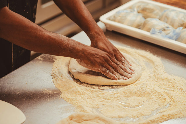 Pâte à pizza maison façonnée à la main sur un plan de travail fariné