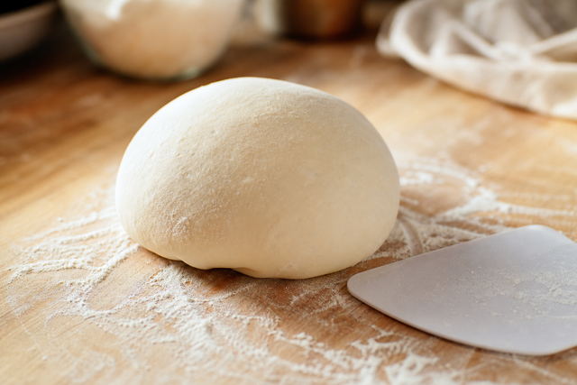 Pâte à pizza pétrie à la main sur un plan de travail, gluten développé et surface lisse