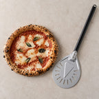 Pelle à pizza tournante à côté d'une pizza montrant la taille de la tête de 23 cm