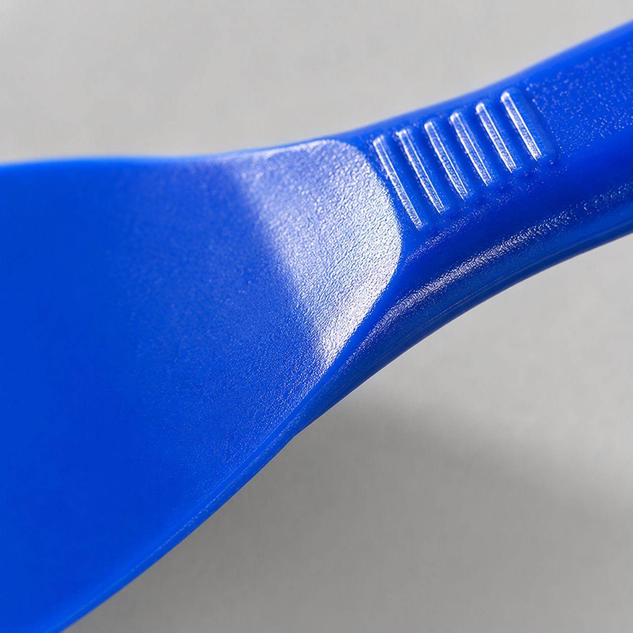 Gros plan sur les stries antidérapantes du manche de la spatule bleue