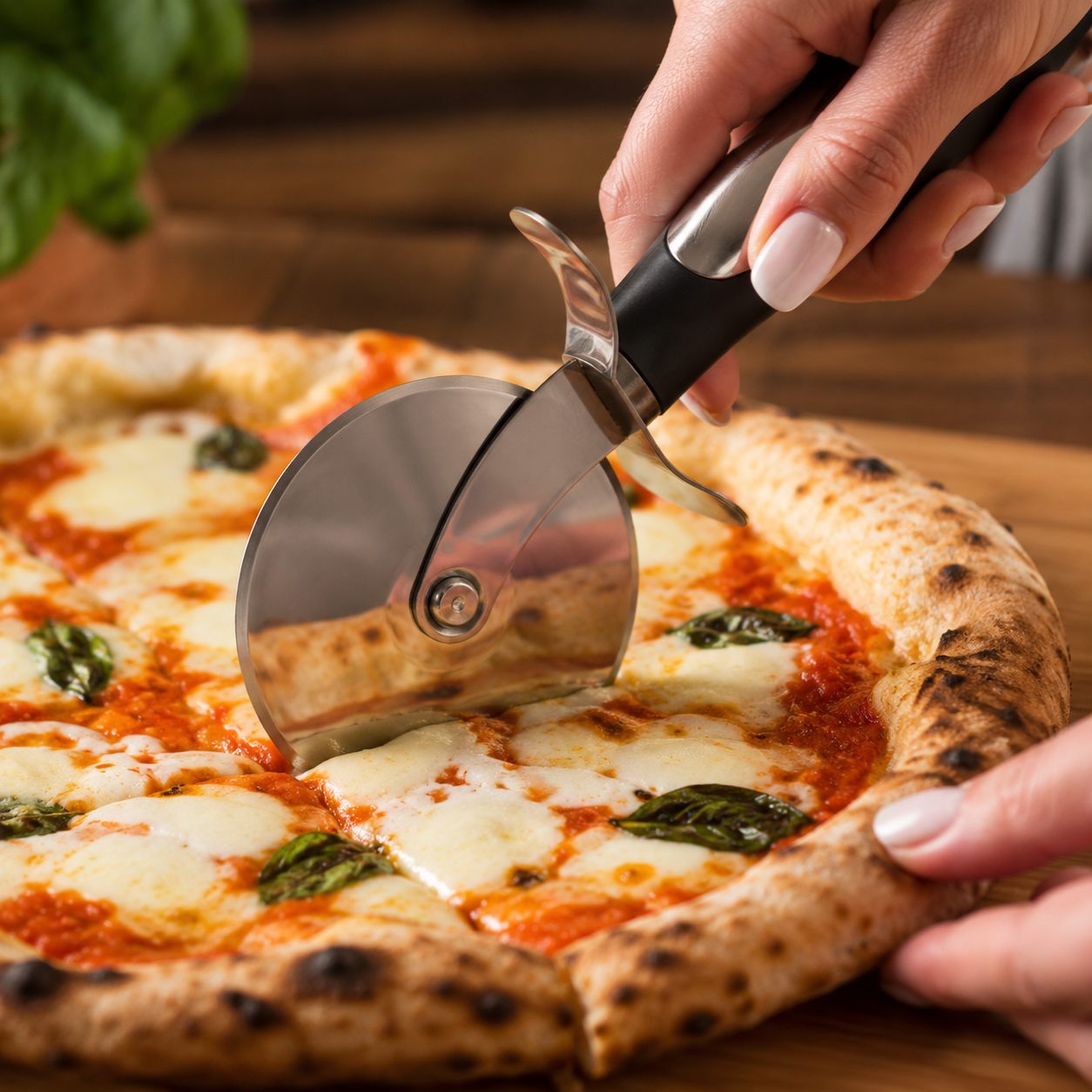 Roulette à pizza qui coupe une pizza margherita maison